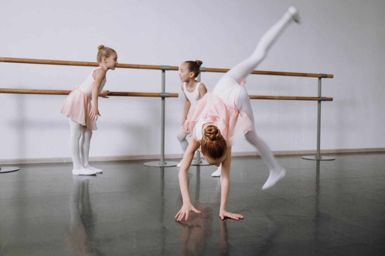 Three young ballerinas practicing ballet moves in a dance studio, enjoying childhood and dance.