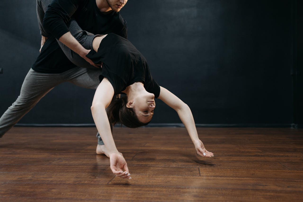 Mastering the First Impression: Your intriguing post title goes here A man and woman performing dynamic dance moves on a wooden floor indoors.